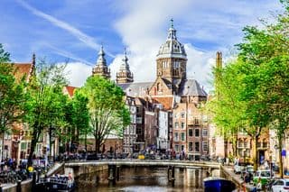 Amsterdam's Iconic Canal Houses and Church under Blue Skies