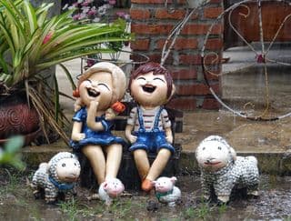Children Laughing with Sheep Statues in Rain
