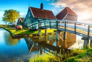 Wooden Bridge Over Dutch Canal Reflecting Traditional Houses