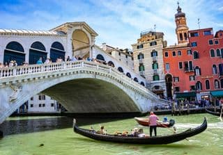 Gondolas glide beneath the Rialto Bridge in Venice