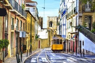 A Bright Yellow Tram Climbs Through Lisbon's Old Streets