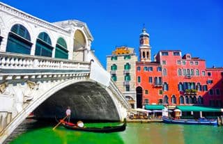Gondolier Paddling Under the Rialto Bridge in Venice