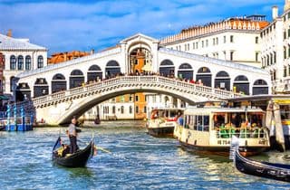 Gondolier Paddling Past the Rialto Bridge in Venice