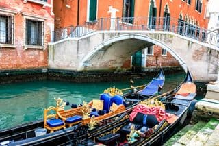 Gondolas moored beneath an ornate bridge in Venice, Italy