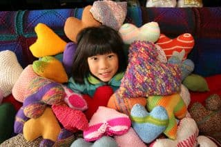 Child Amidst Vibrant Heart Pillows