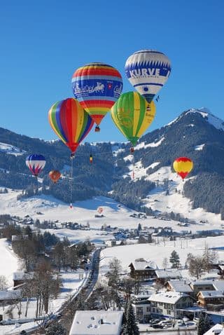 Vibrant Hot Air Balloons Over Snowy Swiss Village