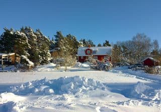 Snow-covered Red Cottage in Swedish Landscape