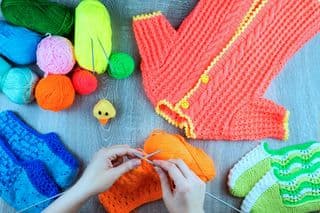 Hands Crafting an Orange Baby Cardigan