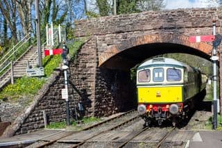 A Heritage Train Exiting an Old Stone Tunnel Bridge