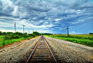 Railroad Tracks Vanishing into the Distance Under Stormy Skies